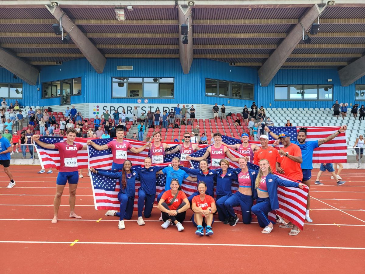 The United States track team gathers for a photo holding their American flags.