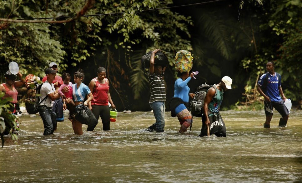 Immigrants wade through the water of a rushing river, hoping to safely complete their journey to America. 