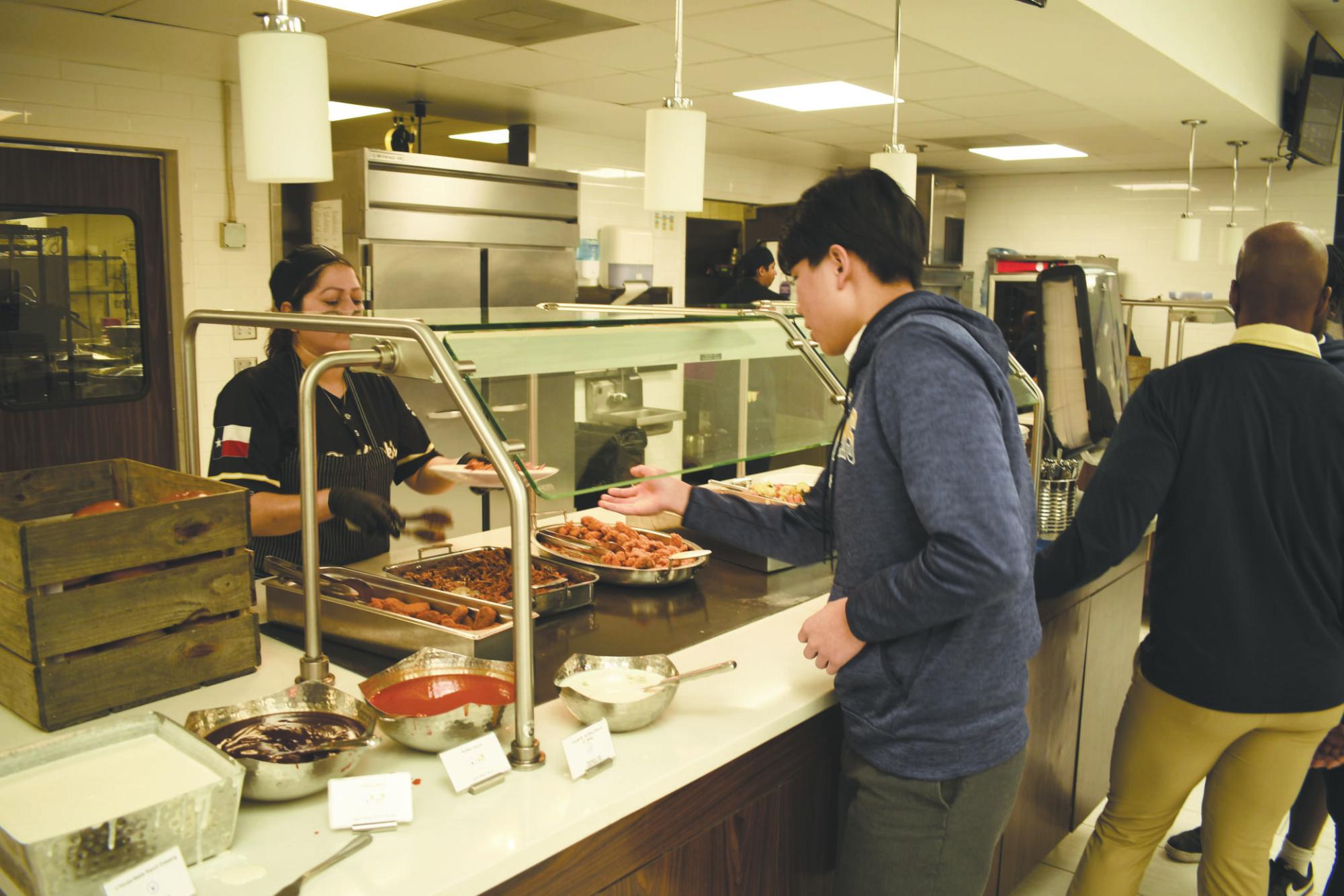 Sophomore Richard Wang reaches for his plate after choosing a variety of foods.