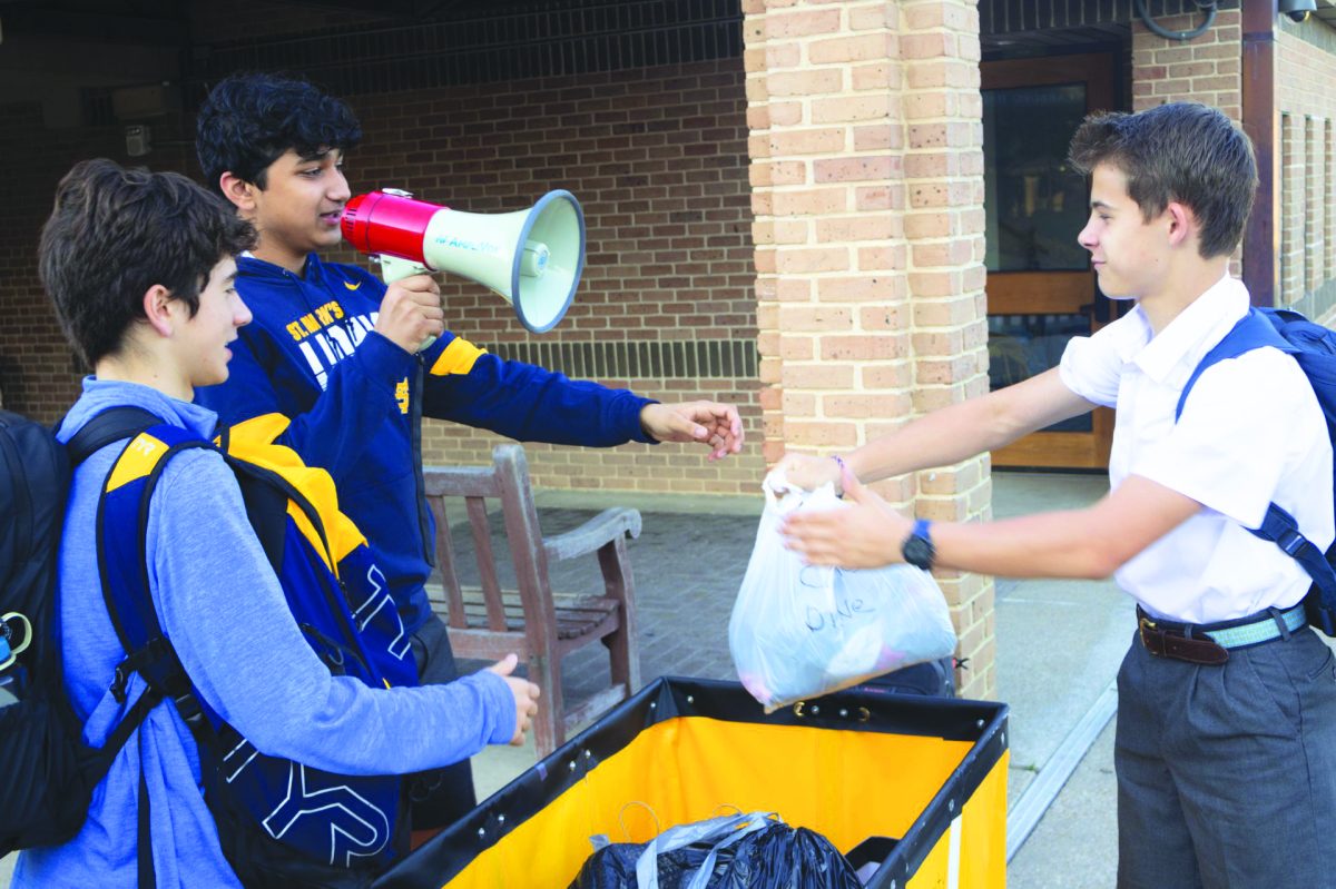 Community Service Board Members recieve a donation while calling students being dropped off to donate to the annual Clothing Drive.