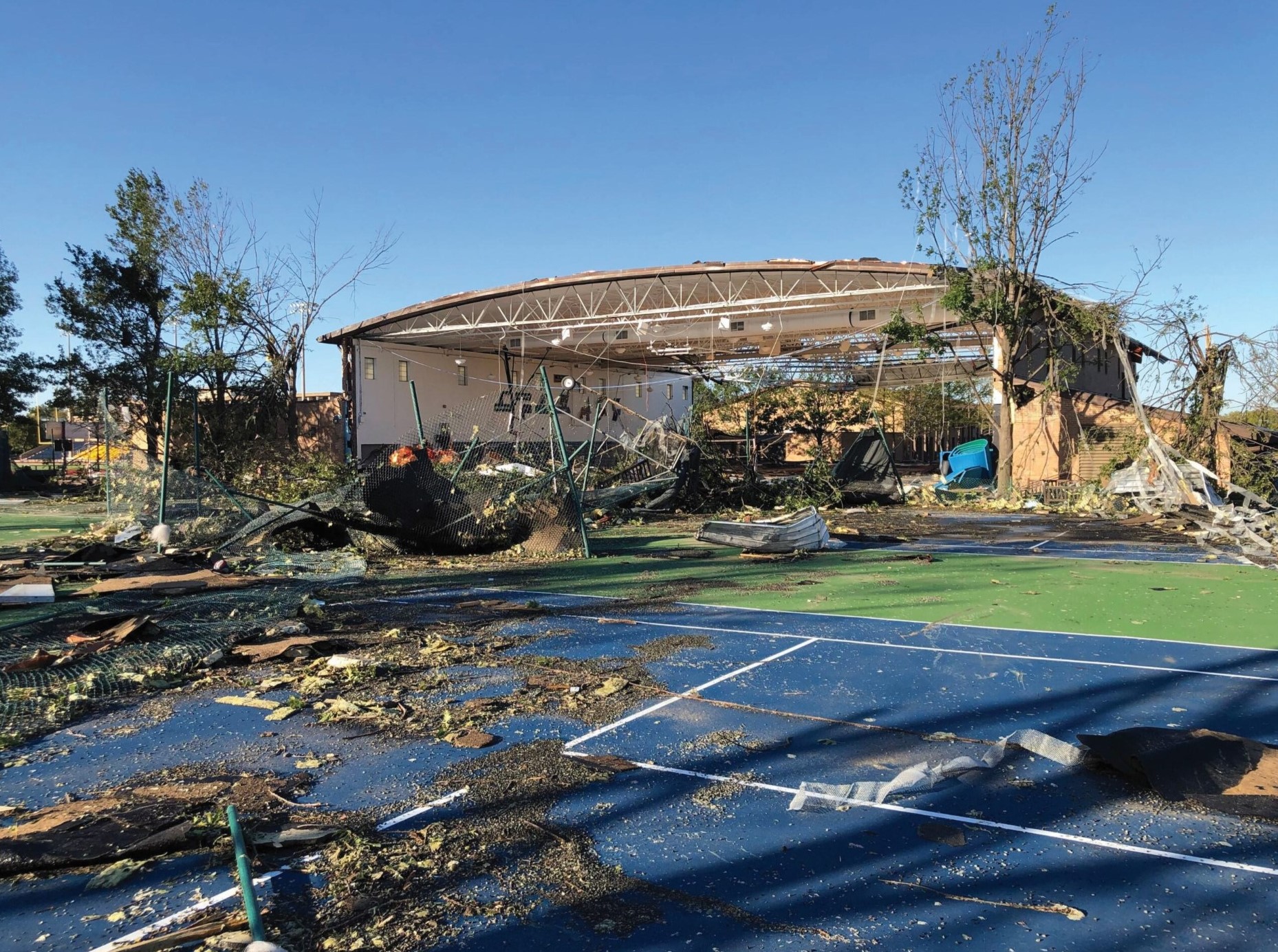 Debris scattered across the tennis courts, with Hicks Gymnasium’s frame barely standing.