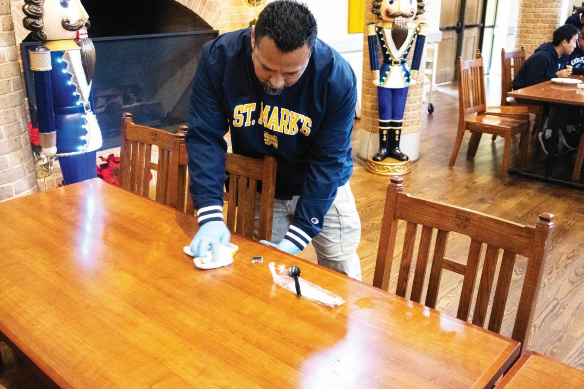 A staff member diligently wipes the lunch table, preparing it for the Lower Schoolers after Upper School lunch.