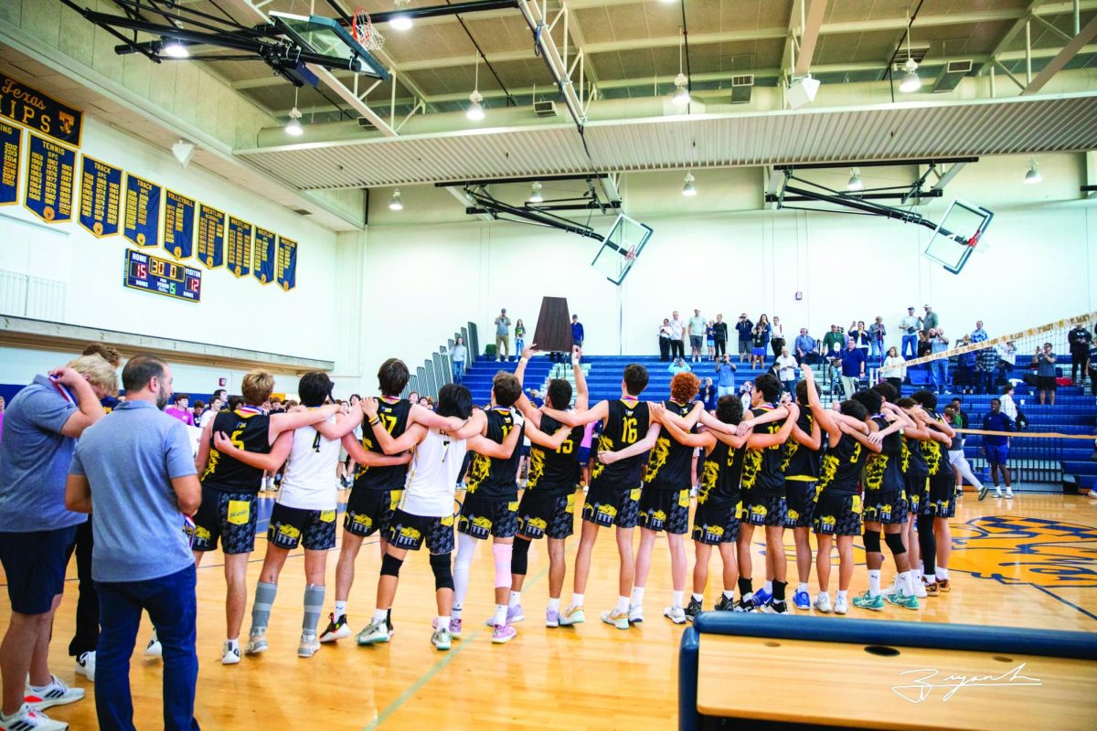 Members of the volleyball team lock arms, celebrating and singing the Alma Mater while waving back and forth after defeating Episcopal High School for the SPC title.