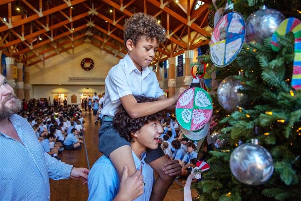 Senior Owen Park carries his little buddy on his shoulders as they hang an ornament on the tree.