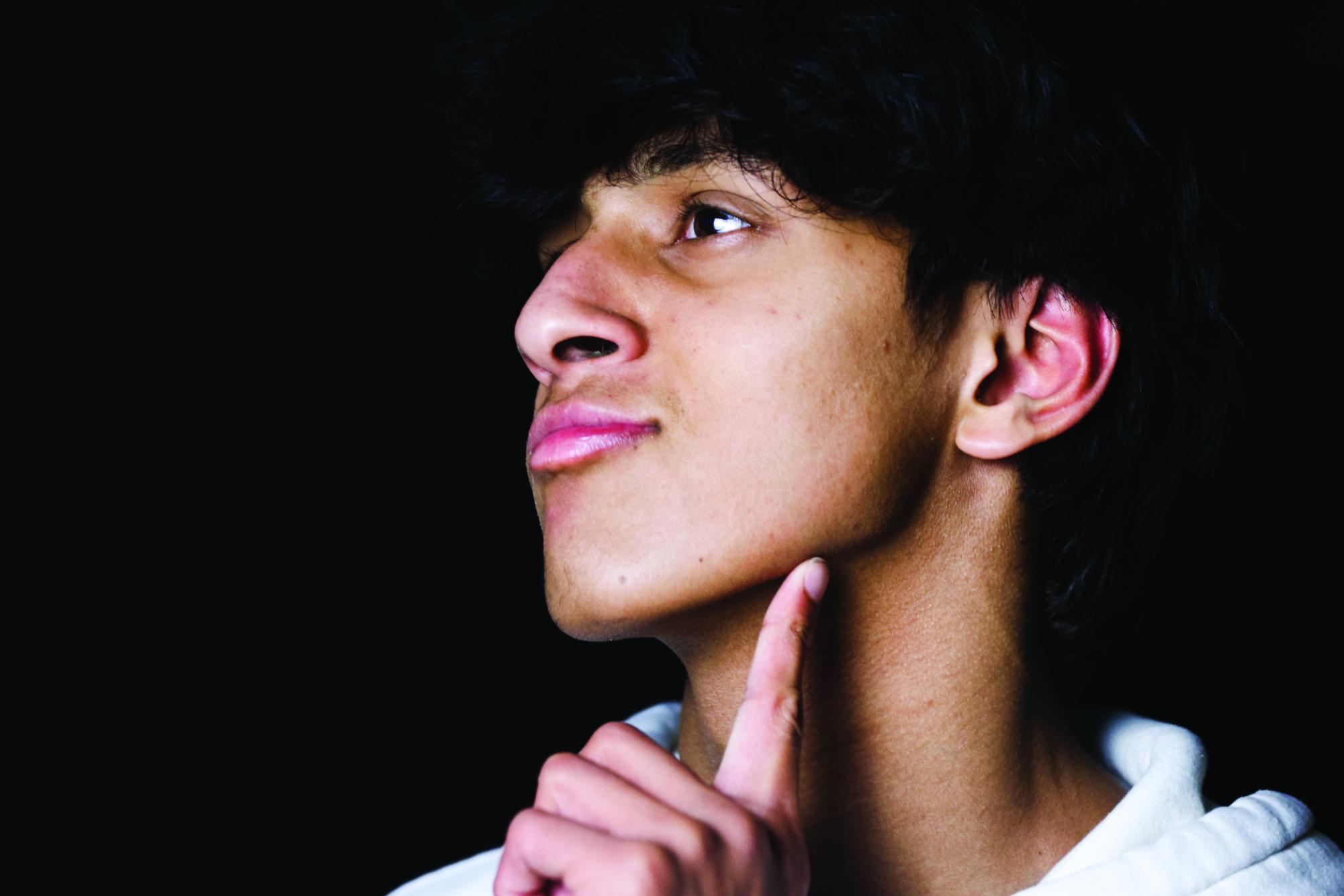 A student points to his jaw, showing off his jawline as he mews 