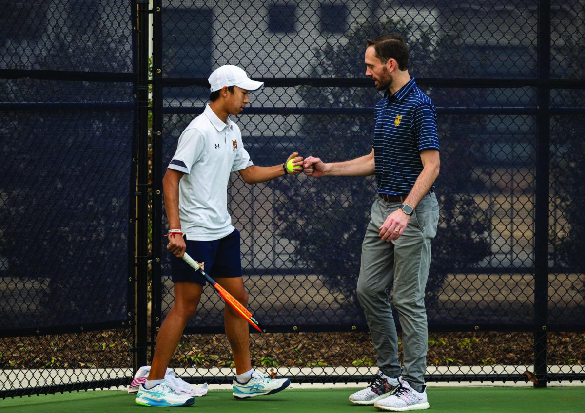 Tennis coach Christian Nagy and Freshman Bryan Li fist-bump during a tennis practice.