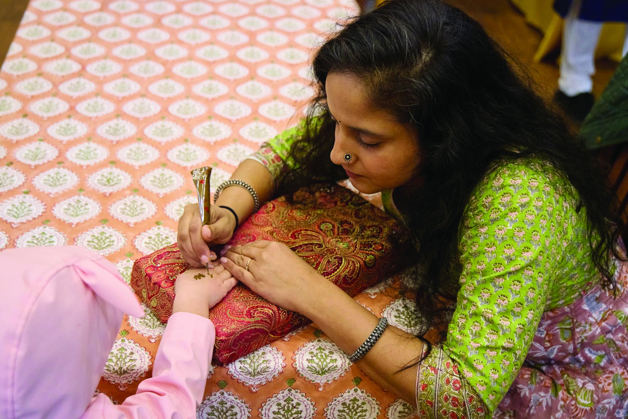 Volunteer paints a visitor's hand.