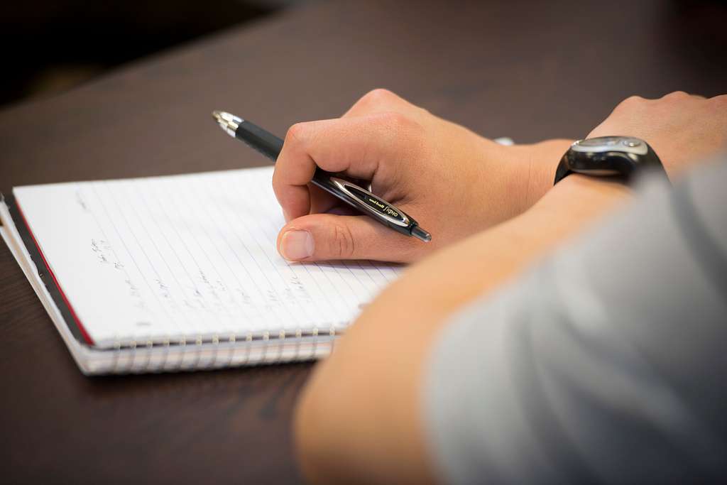 Student takes notes on a spiral notebook