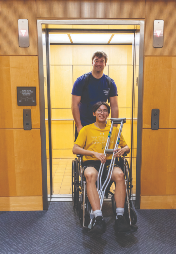 Senior Henry Estes helps sophomore Dylan Bosita out of an elevator on campus 