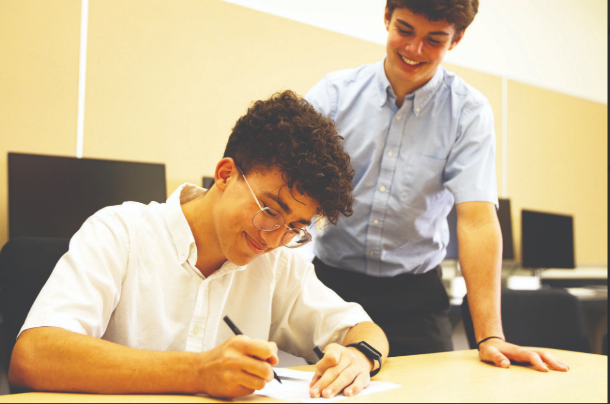 A senior watches over an underclassman as he completes on his homework