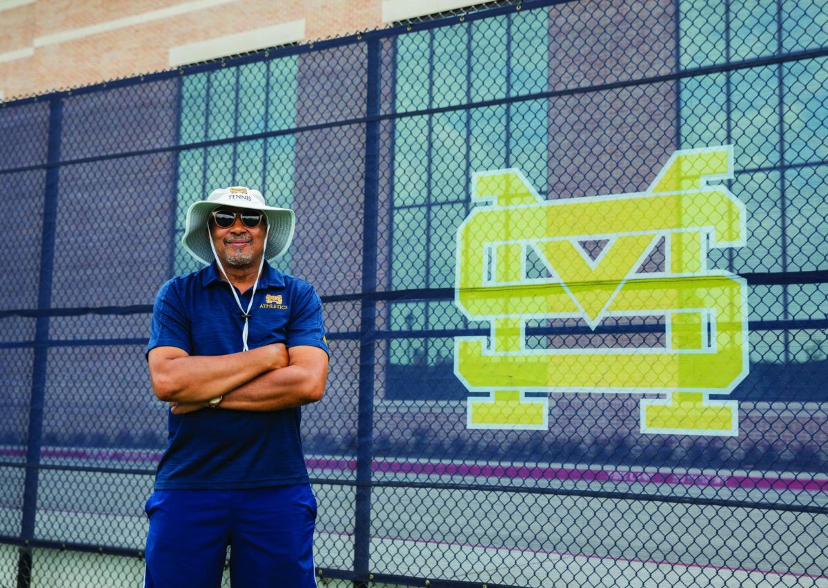 Turner poses next to the school logo in the Albert G. Hill, Sr. family tennis courts