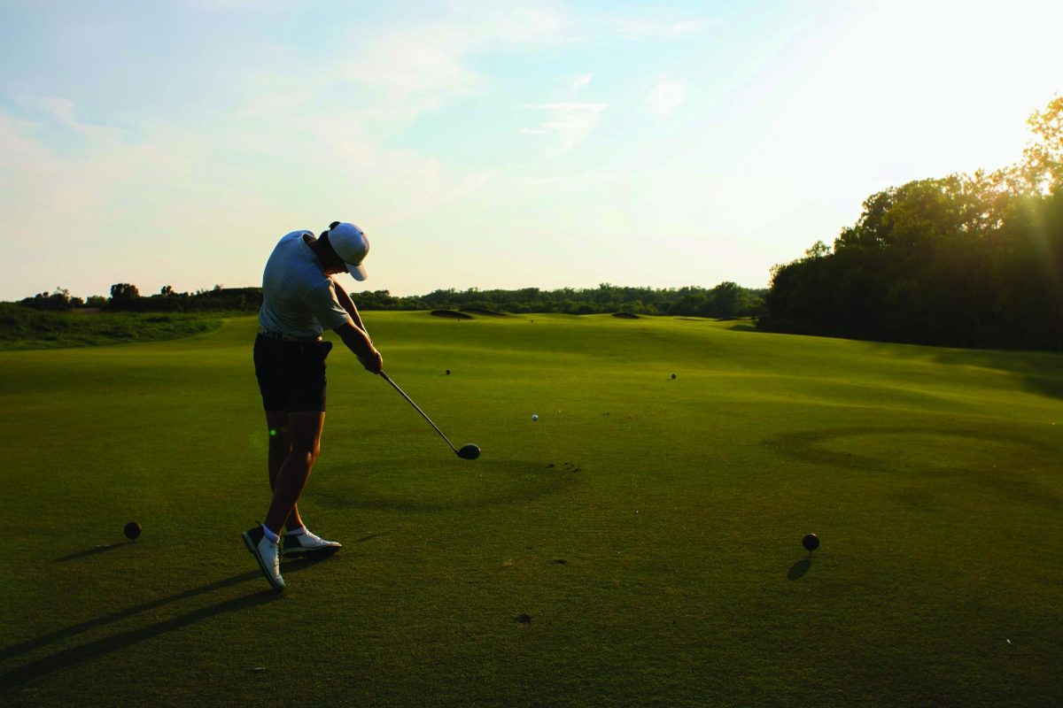 Senior Jonathan Lobel tees up at Trinity Forest Golf Club to practice his swing.