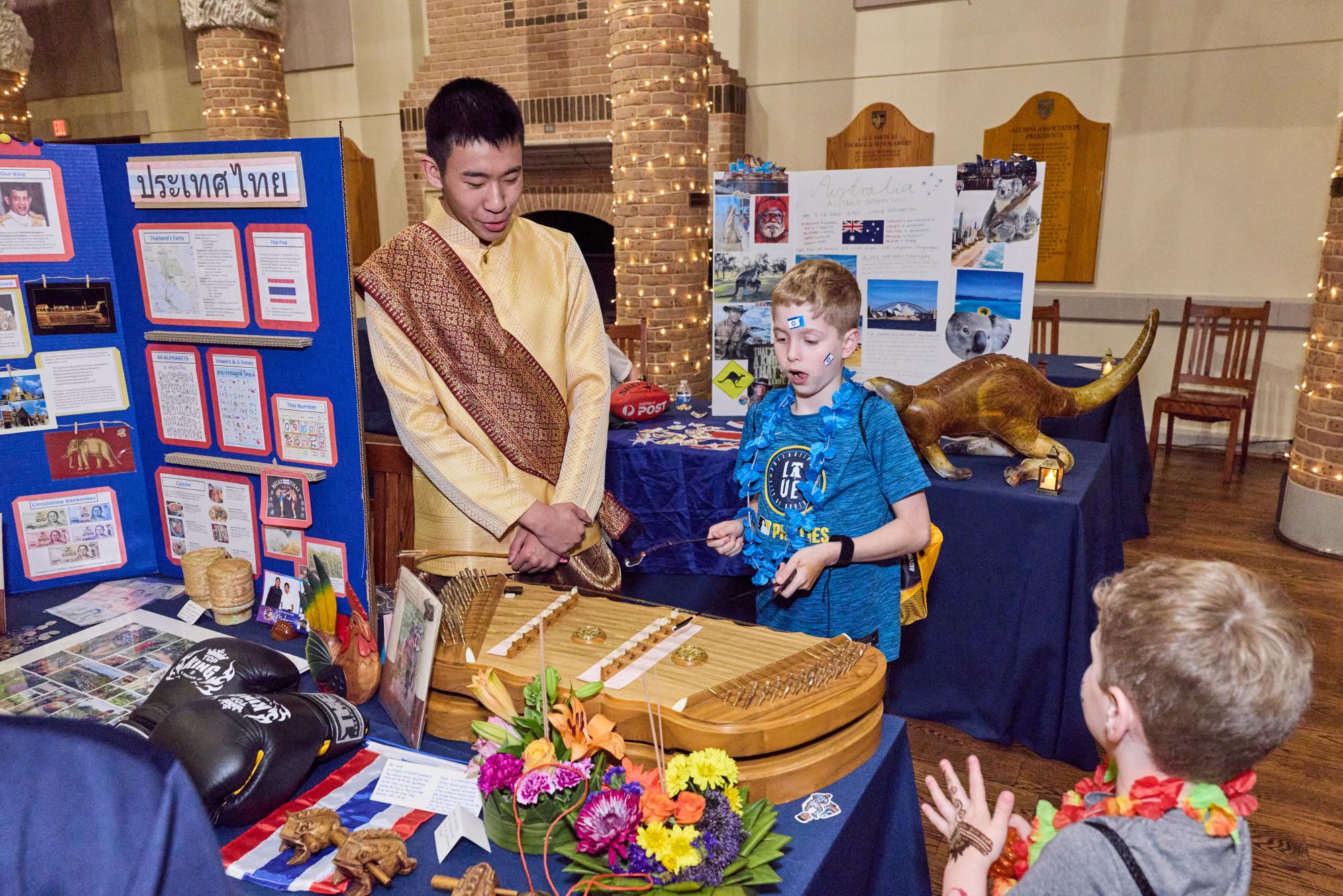 A student  shows off his  cultural display table to a younger Marksman.