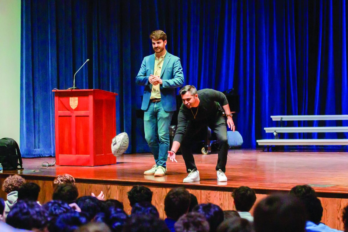 Kahan Chavda ’12 and Roland Salatino ’12 present during Upper School Assembly, showing a football made from invasive Burmese python skin.
