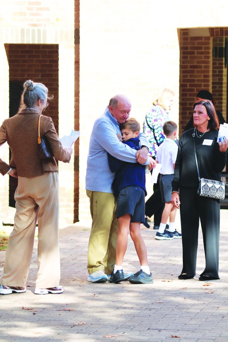 A grandfather tightly embraces his son on grandparents day, one of the school’s long running traditions in which students’ grandparents accompany them to school.