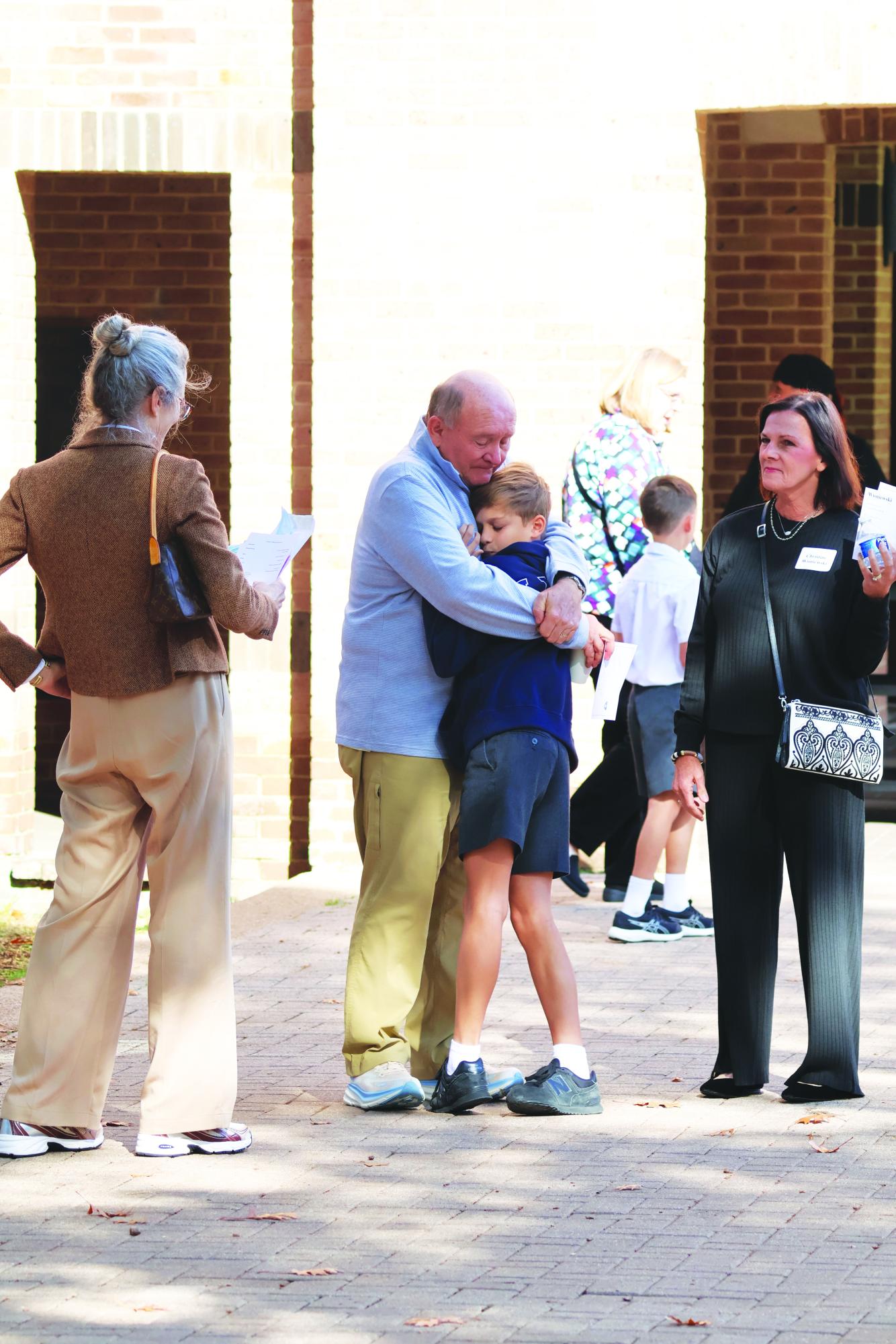 A grandfather tightly embraces his son on grandparents day, one of the school’s long running traditions in which students’ grandparents accompany them to school.